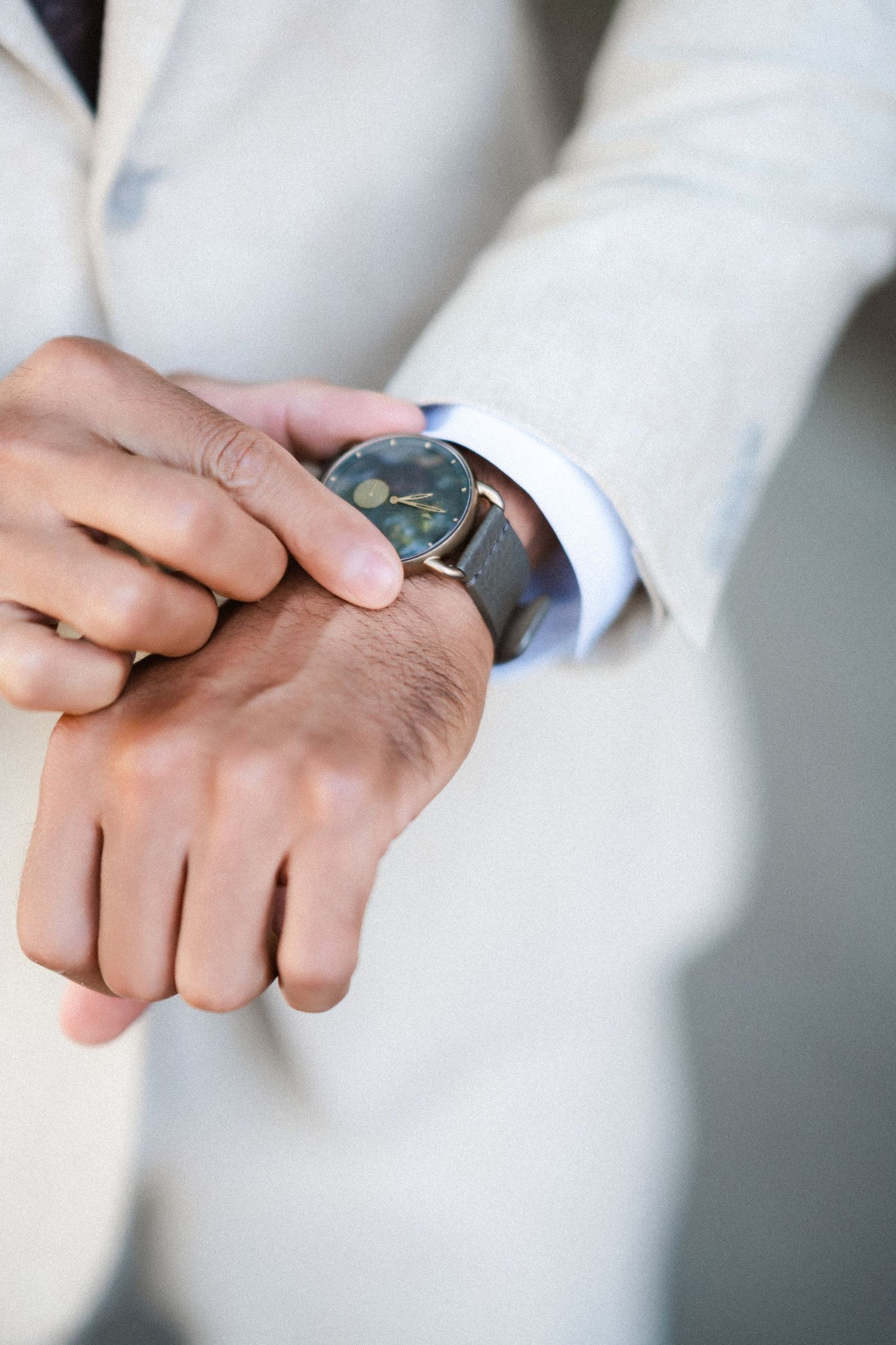 Detail shot of hands showing wedding rings against light background.