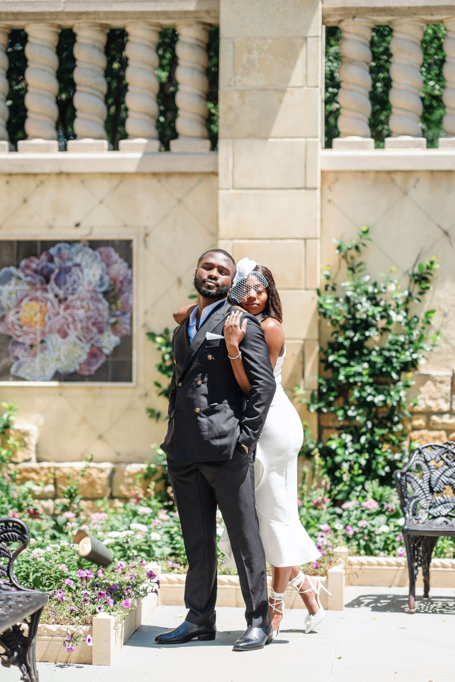 A wedding photoshoot in an elegant stone courtyard with ivy-covered columns and garden landscaping.