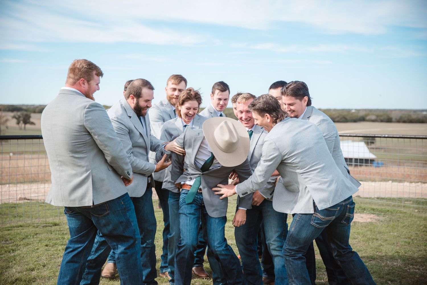 Groomsmen in casual attire celebrate together during outdoor wedding festivities.