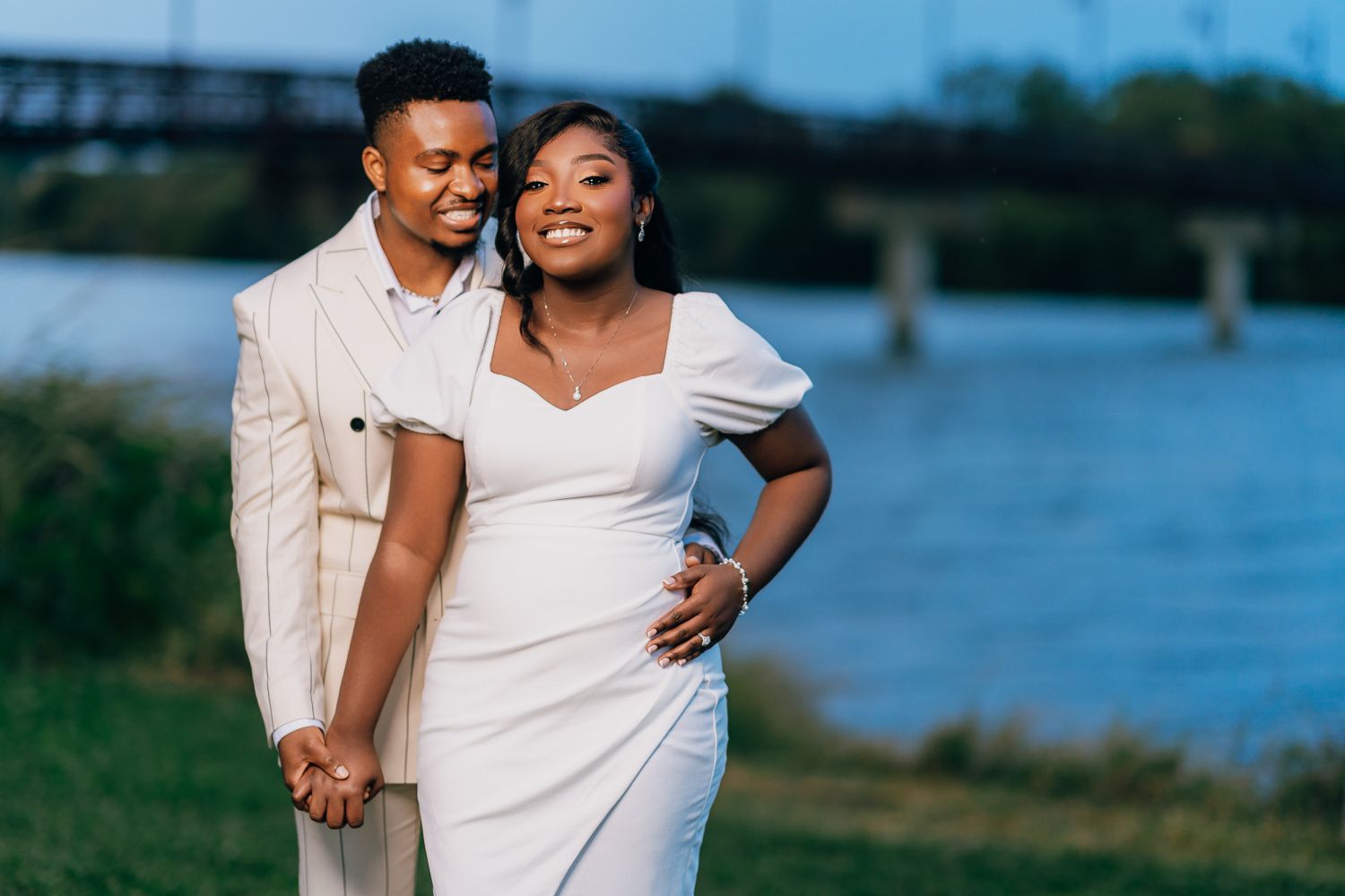 A couple shares tender moments together during a waterfront photoshoot wearing coordinated white outfits.