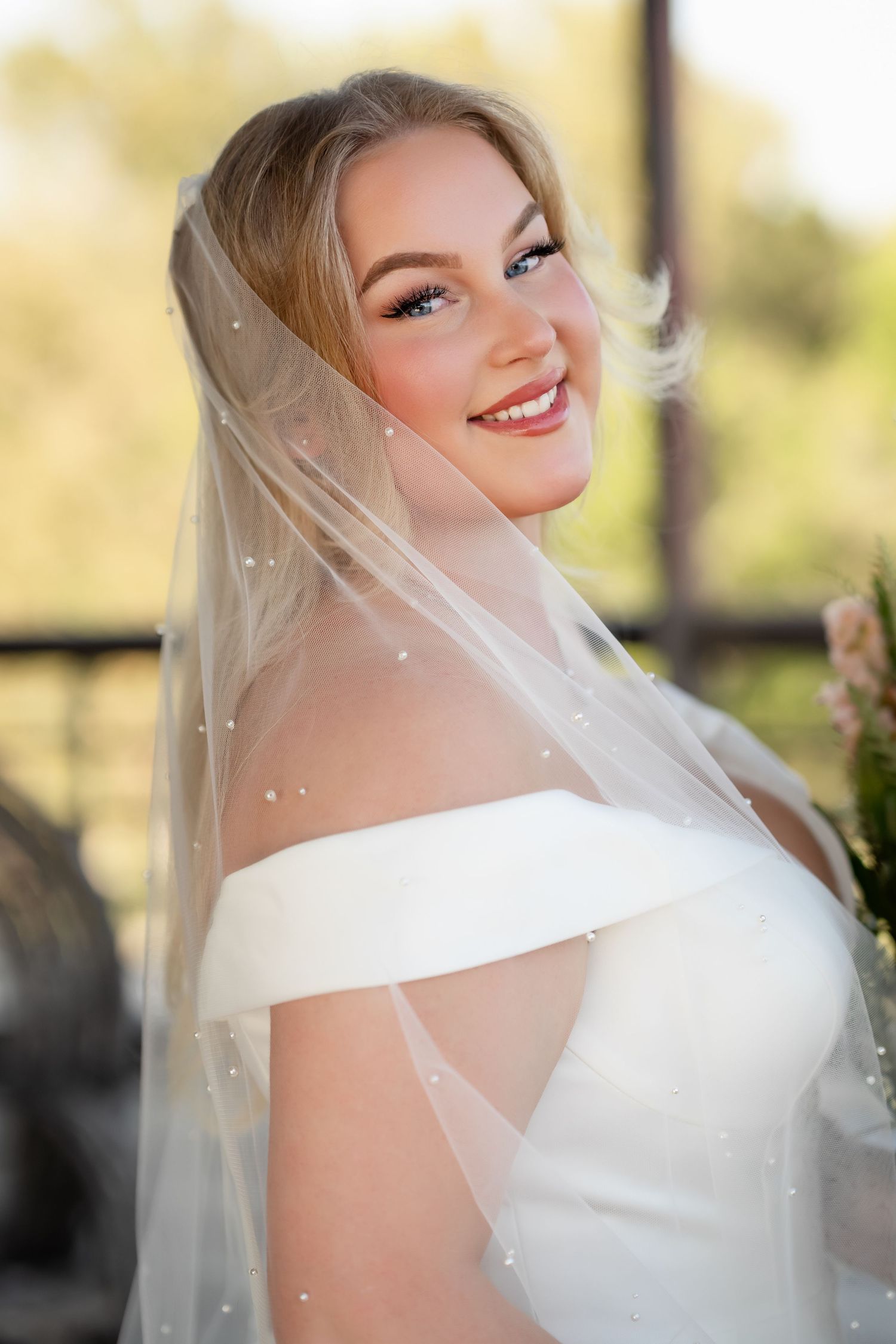Romantic bridal portrait with delicate veil and off-shoulder wedding gown.