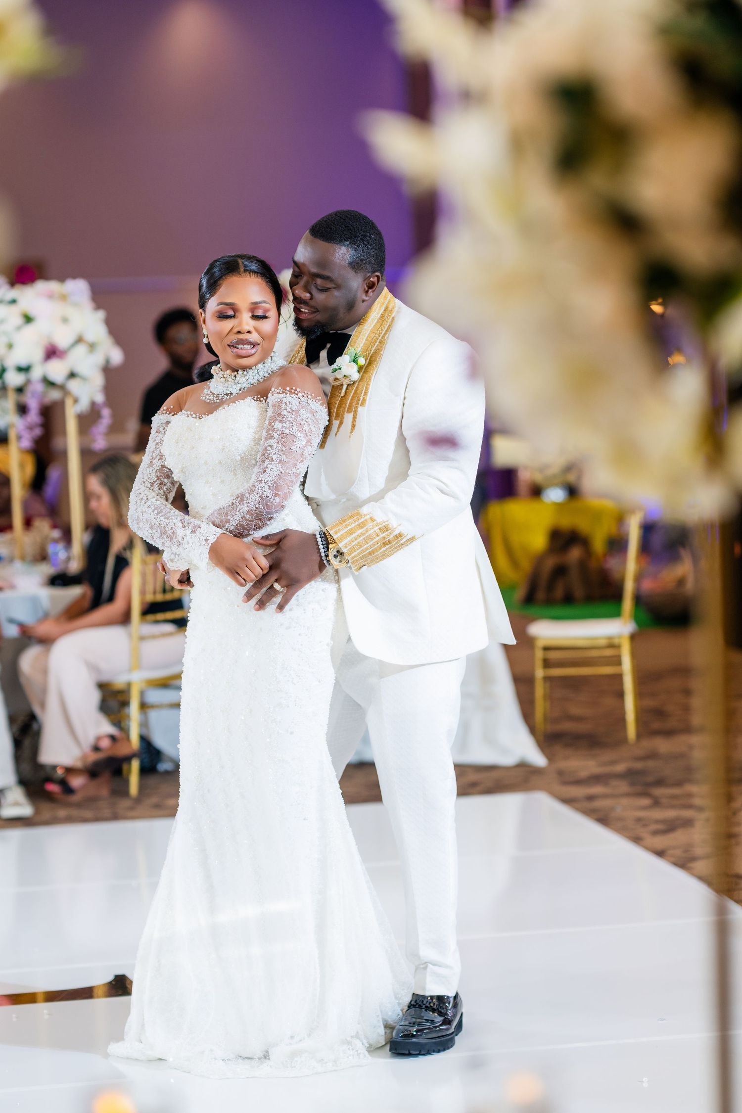 A romantic first dance moment between newlyweds wearing elegant white outfits.