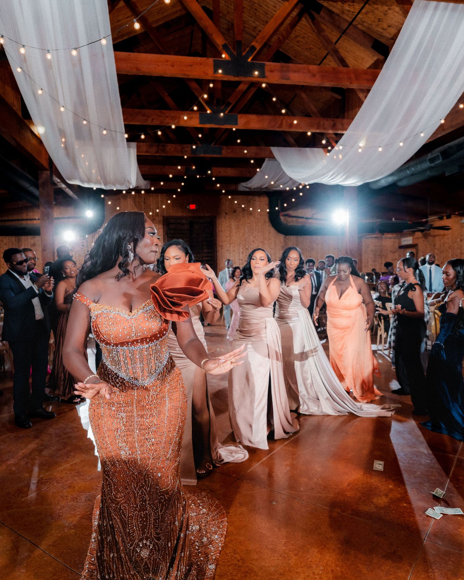Wedding reception dance floor filled with guests under twinkling lights and white draping.
