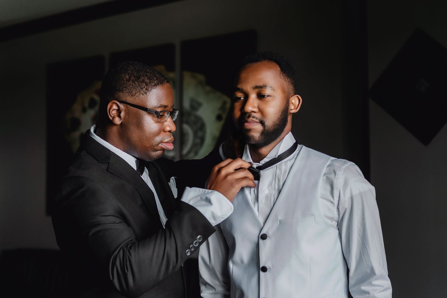Dramatic low-light portrait session featuring groomsmen in formal attire against dark background.