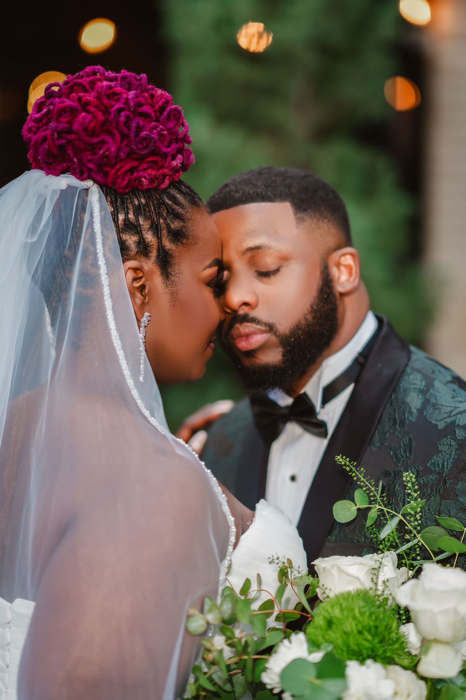 An intimate wedding moment captured with magenta floral details and soft evening lighting.