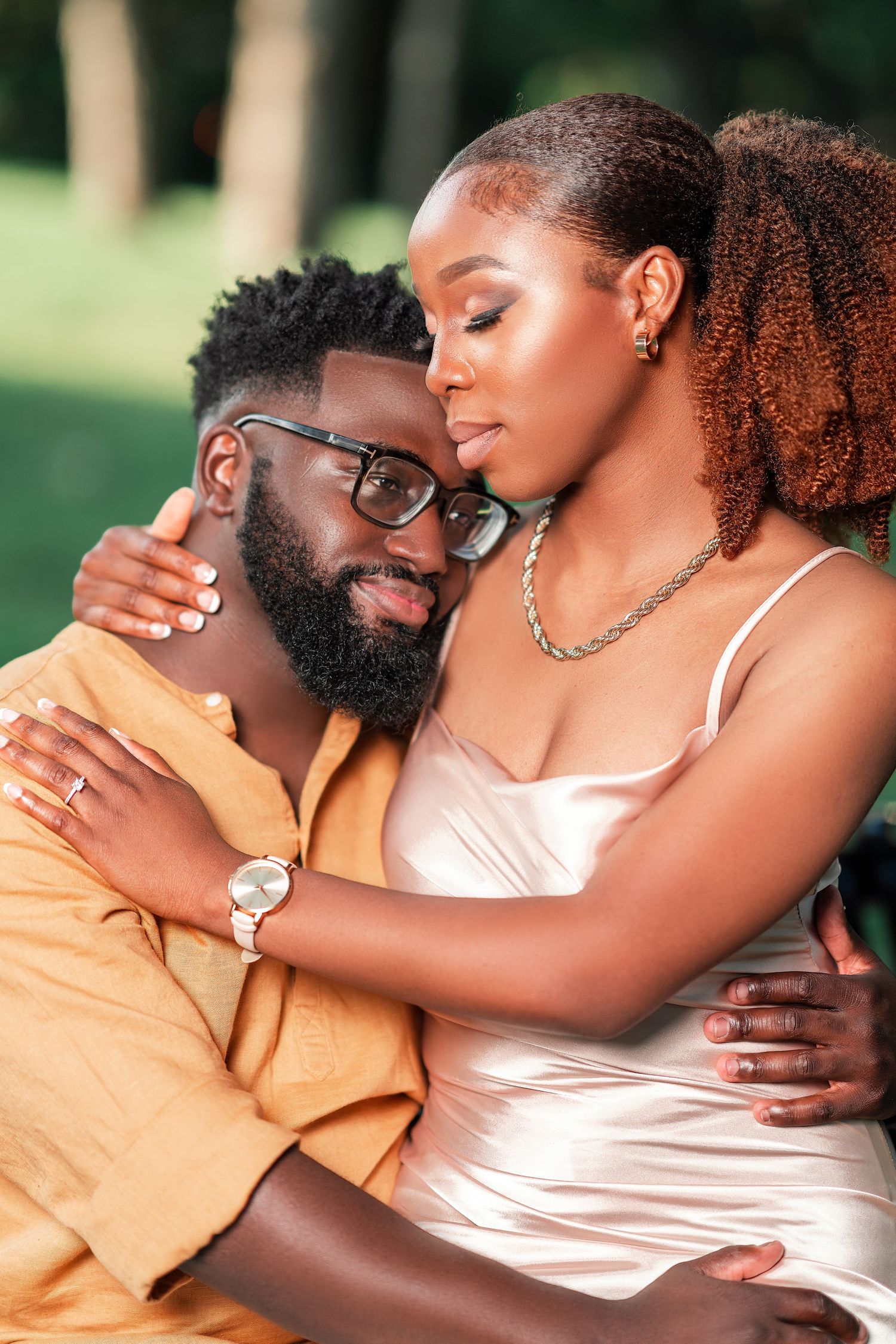A couple in yellow and pink outfits embraces tenderly during an outdoor photoshoot.