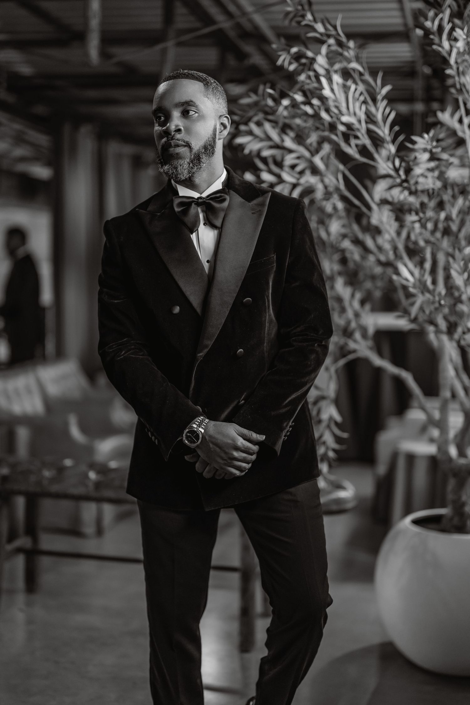 Elegant black and white photo series of a groom in a classic tuxedo posing in an indoor venue.