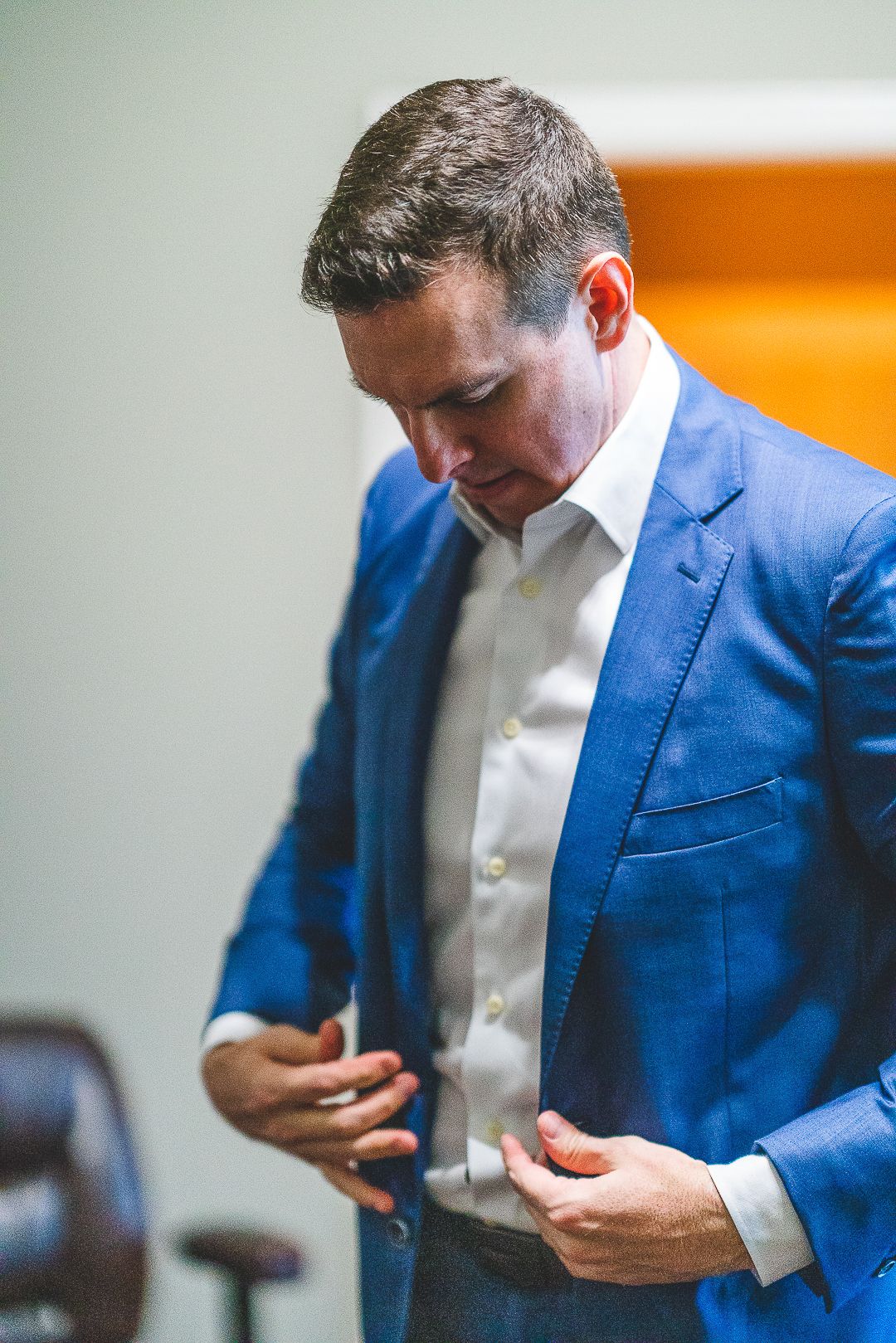 Close-up shot of someone in a blue suit jacket and white shirt checking their phone.