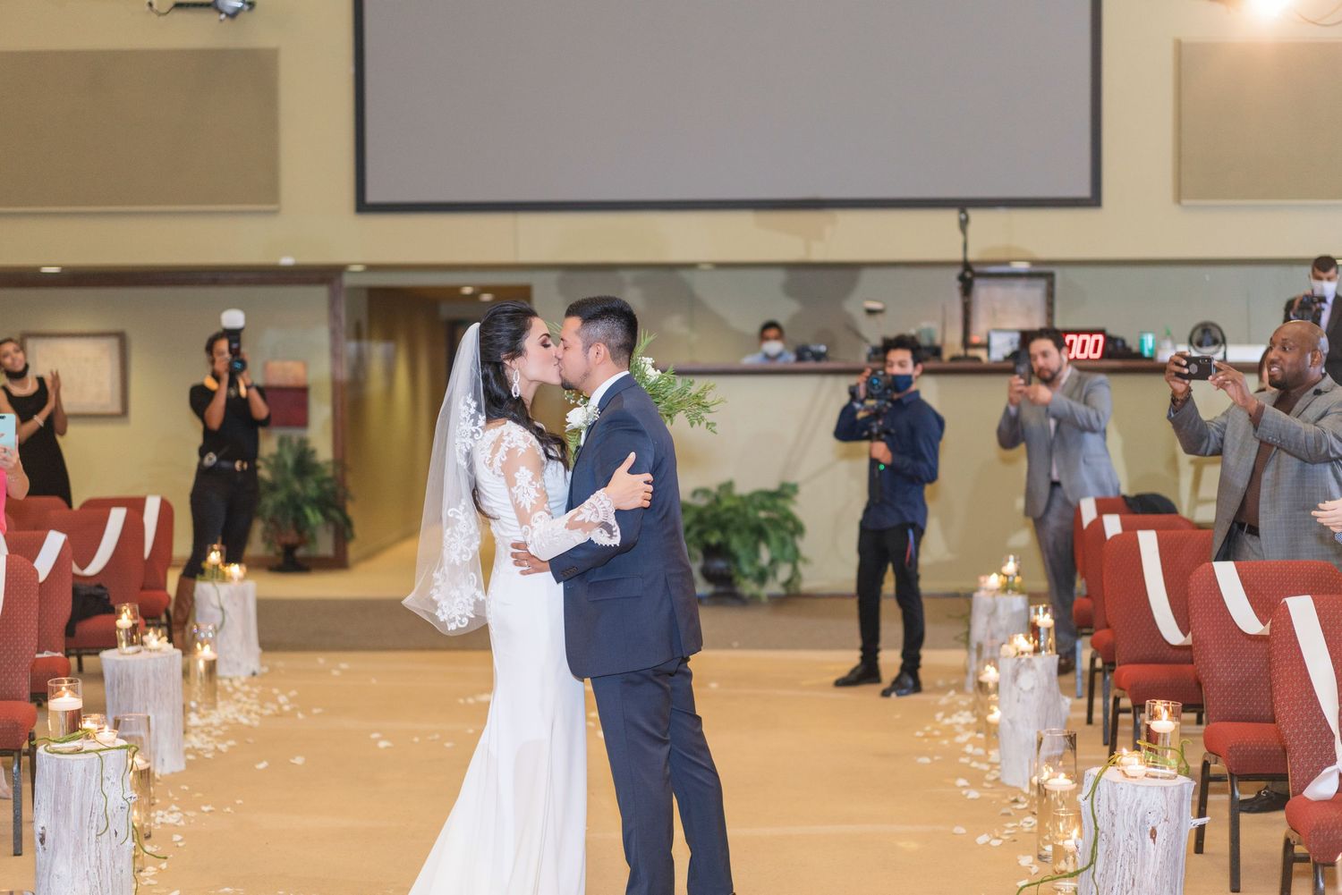 Newlyweds share their first dance in a church hall decorated with candles and rose petals.