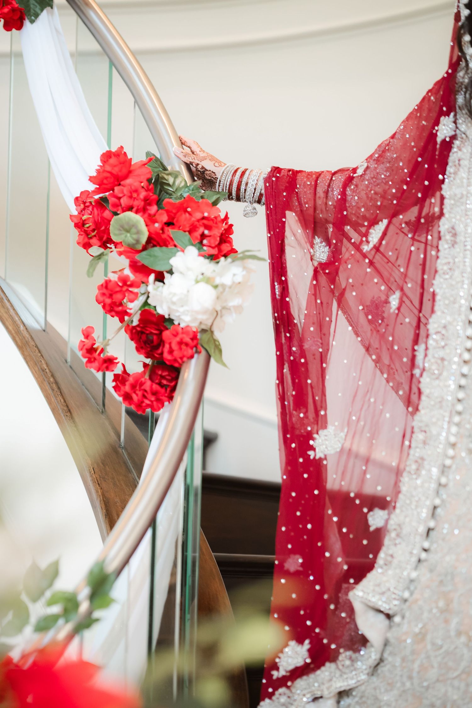 Red and white floral decorations adorning a staircase railing with flowing red fabric.