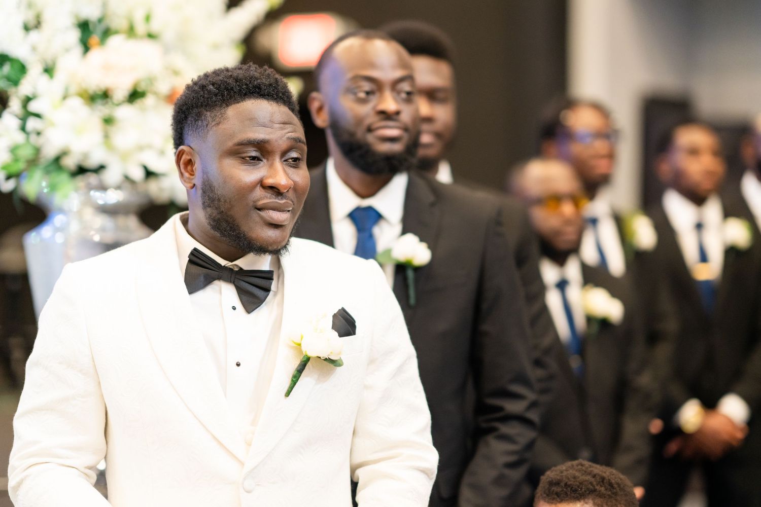 Wedding celebration with guests in formal black and white attire during an indoor reception.