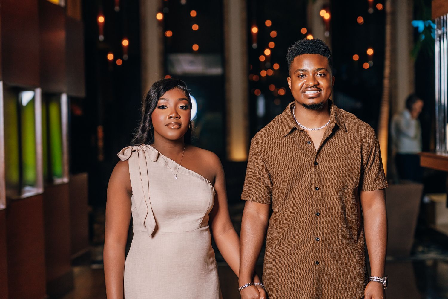 Couple poses together in evening lighting with warm bokeh effects.