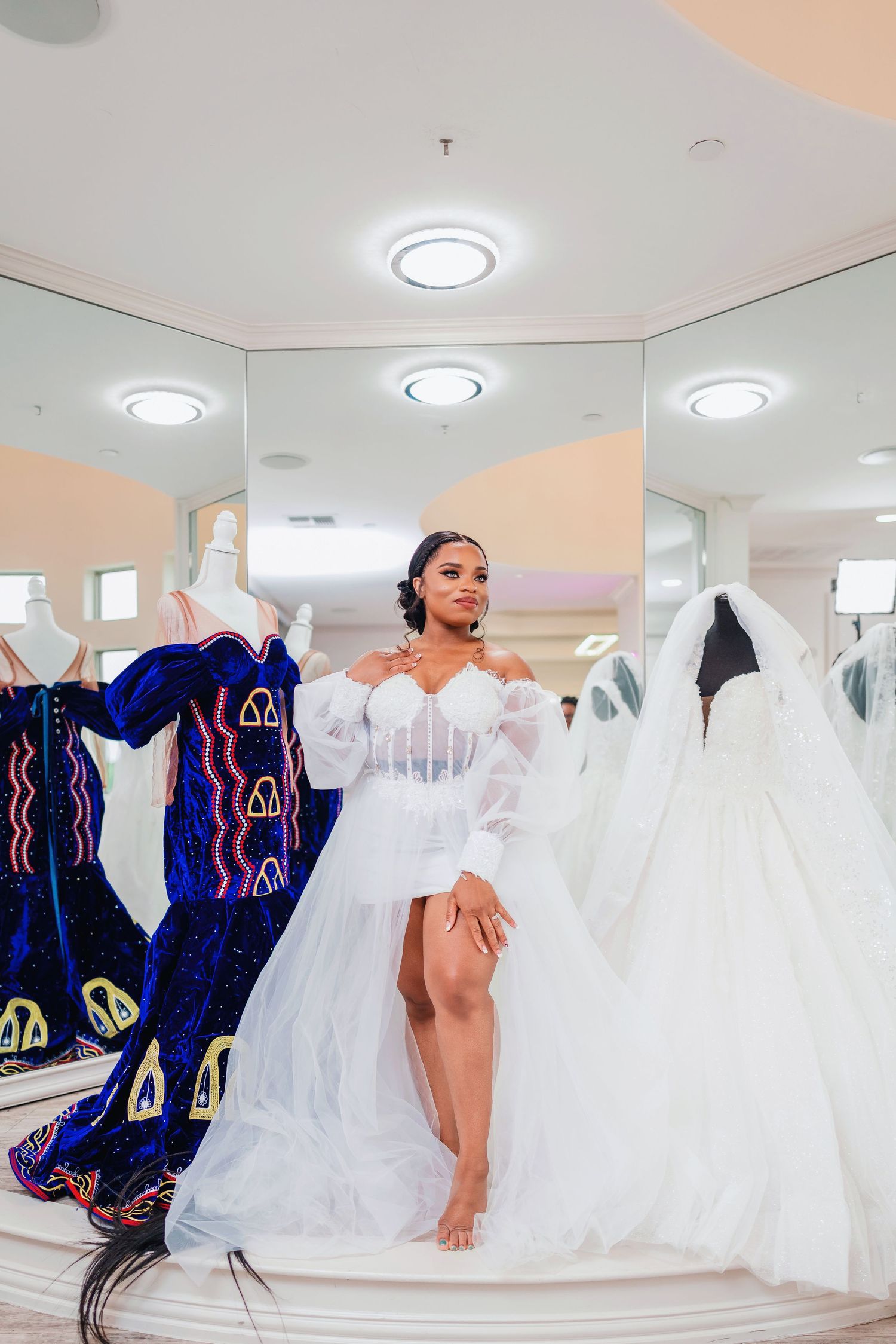 Wedding dress boutique interior showing rows of white gowns with blue ceremonial attire in contrast.