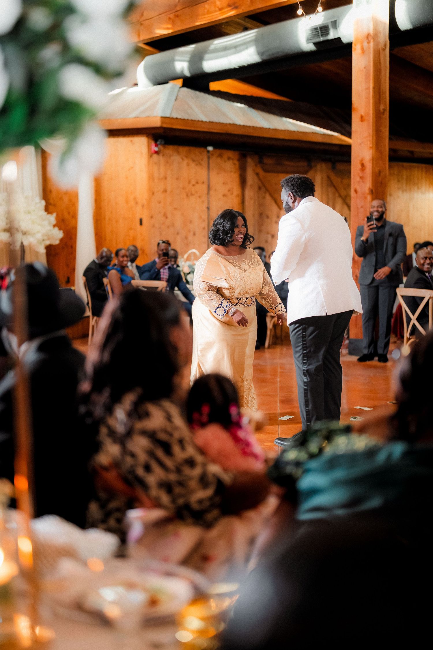 Wedding celebration in a rustic wooden venue with guests watching the festivities.