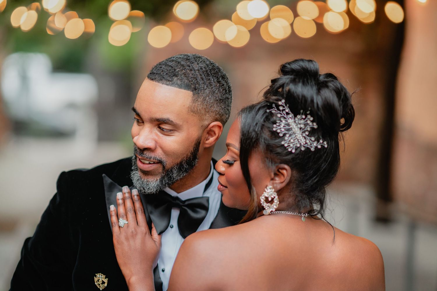 A romantic moment between newlyweds during their wedding celebration with glowing lights in the background.