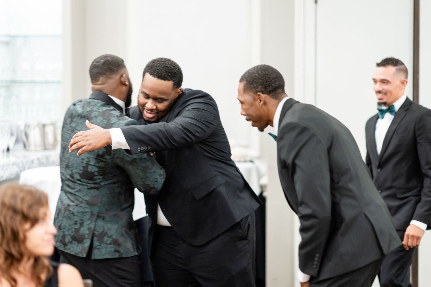 Wedding party members sharing emotional embraces during a celebration.