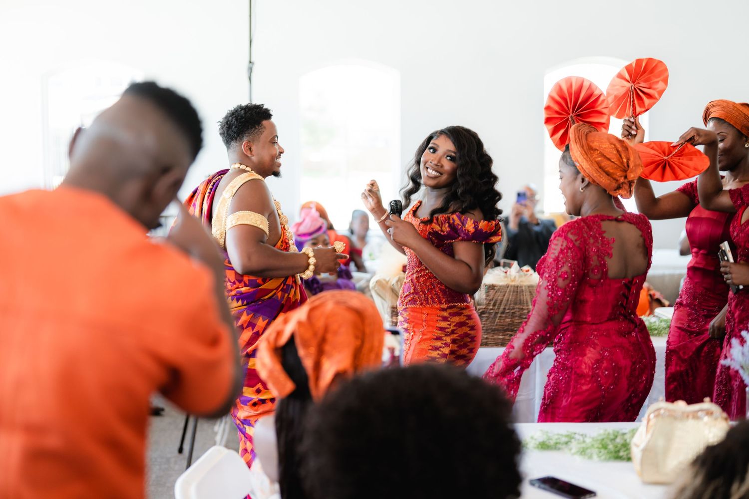 Festive wedding reception with guests in red and orange outfits dancing and enjoying the celebration.