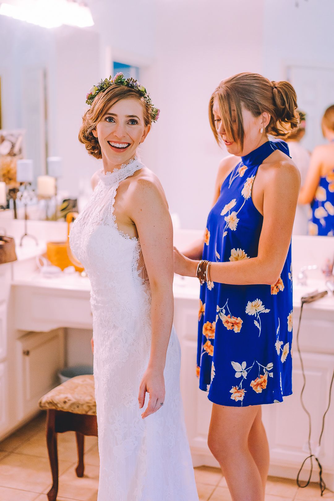 Wedding party members in blue dresses and white gown getting ready in a bright room.