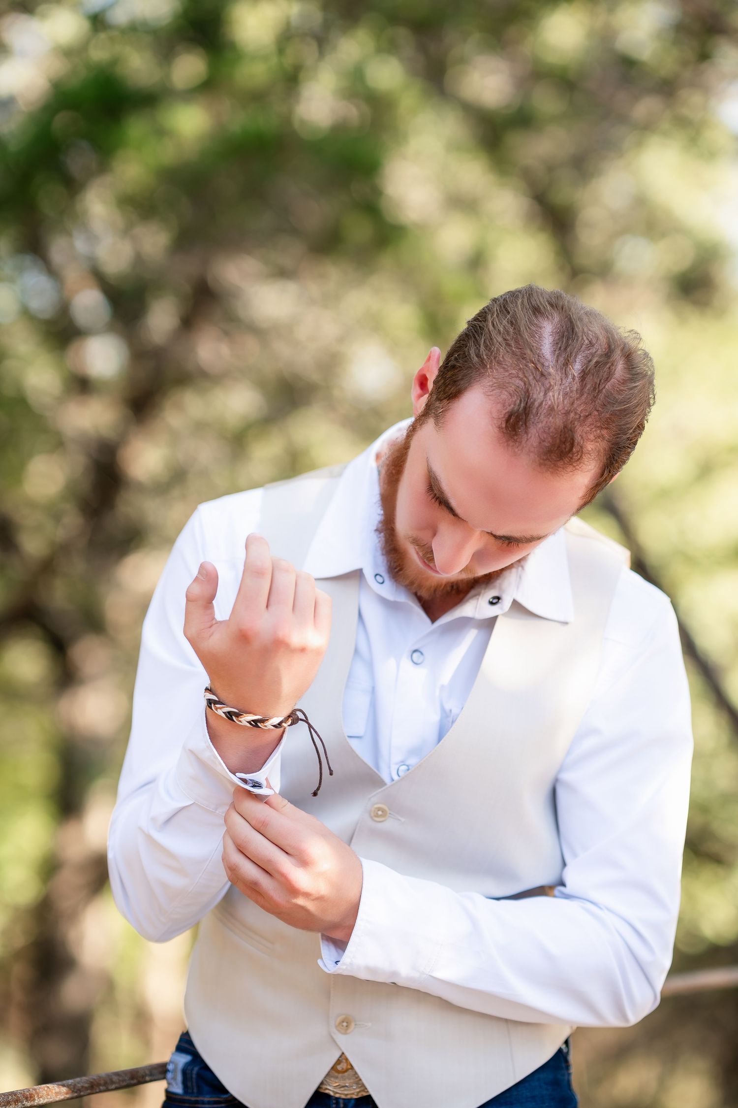 A person in a white dress shirt reacts emotionally during what appears to be a first look moment outdoors.