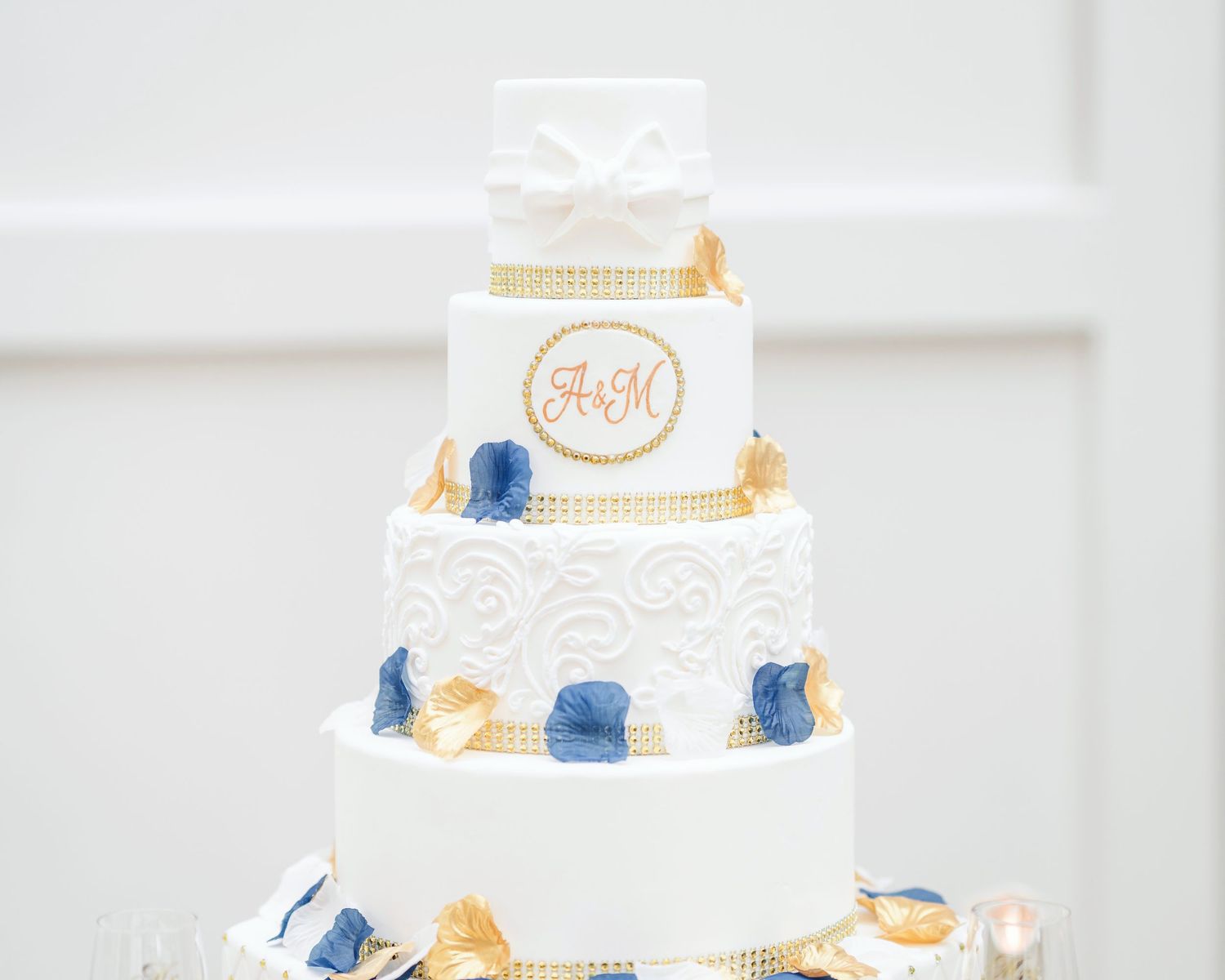 Elegant white and blue tiered wedding cake with gold accents on display.