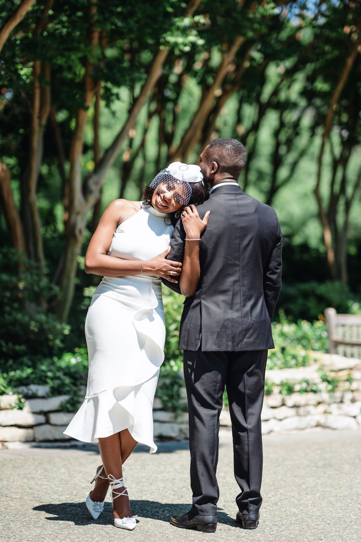 A couple shares a tender moment during their outdoor wedding photoshoot in a lush garden setting.