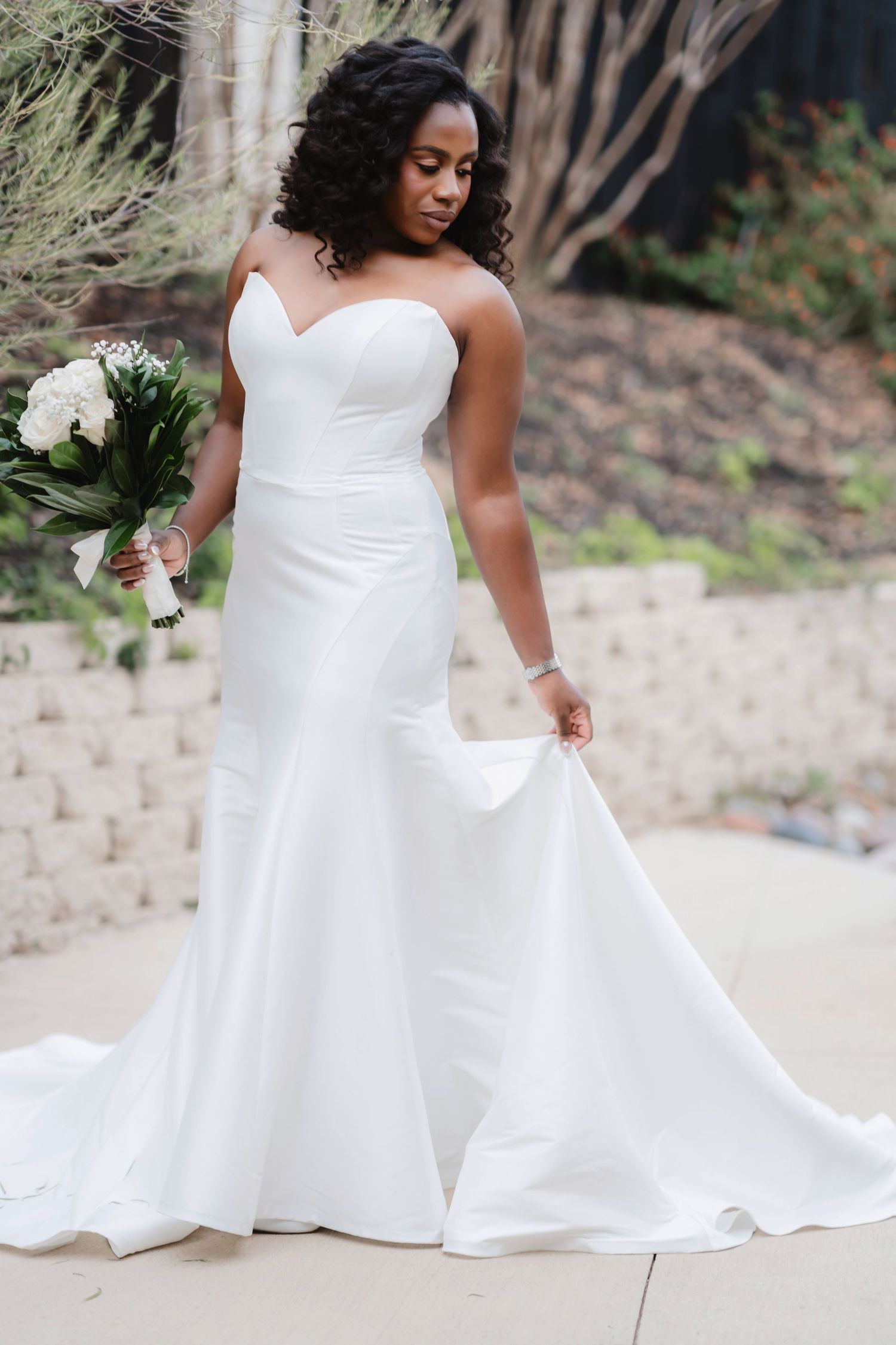 Elegant bride twirls in a flowing white wedding gown on a sandy beach.