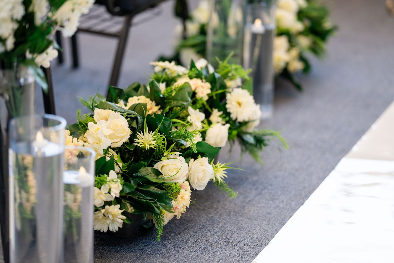 Elegant white floral arrangements line the wedding ceremony aisle.