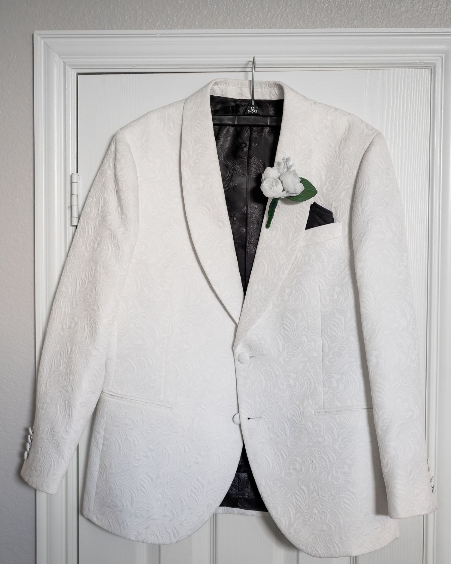 White formal blazers hanging on display against a light gray wall.