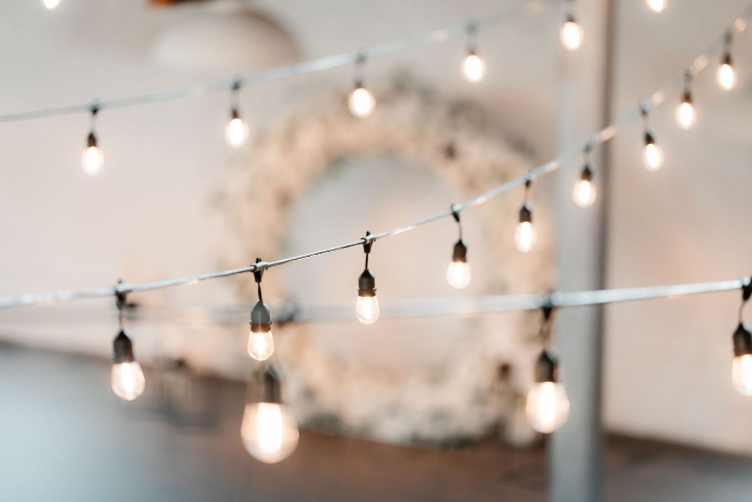 String lights and a floral wreath create a romantic ambiance against a light colored wall.