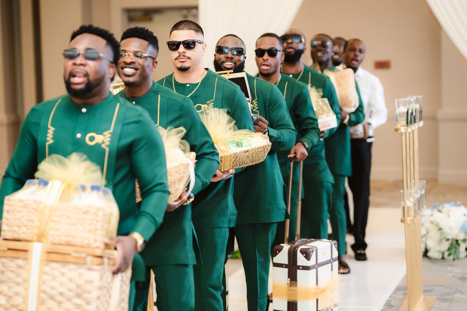 Groomsmen in emerald green suits walking in formation at wedding ceremony.