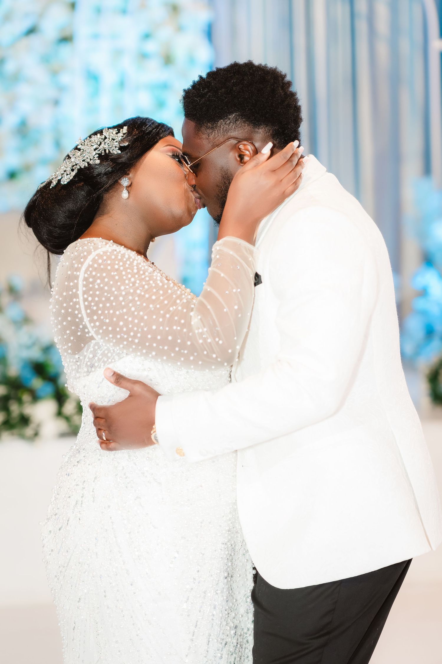 Romantic wedding couple sharing an intimate moment against a blue and white floral backdrop.