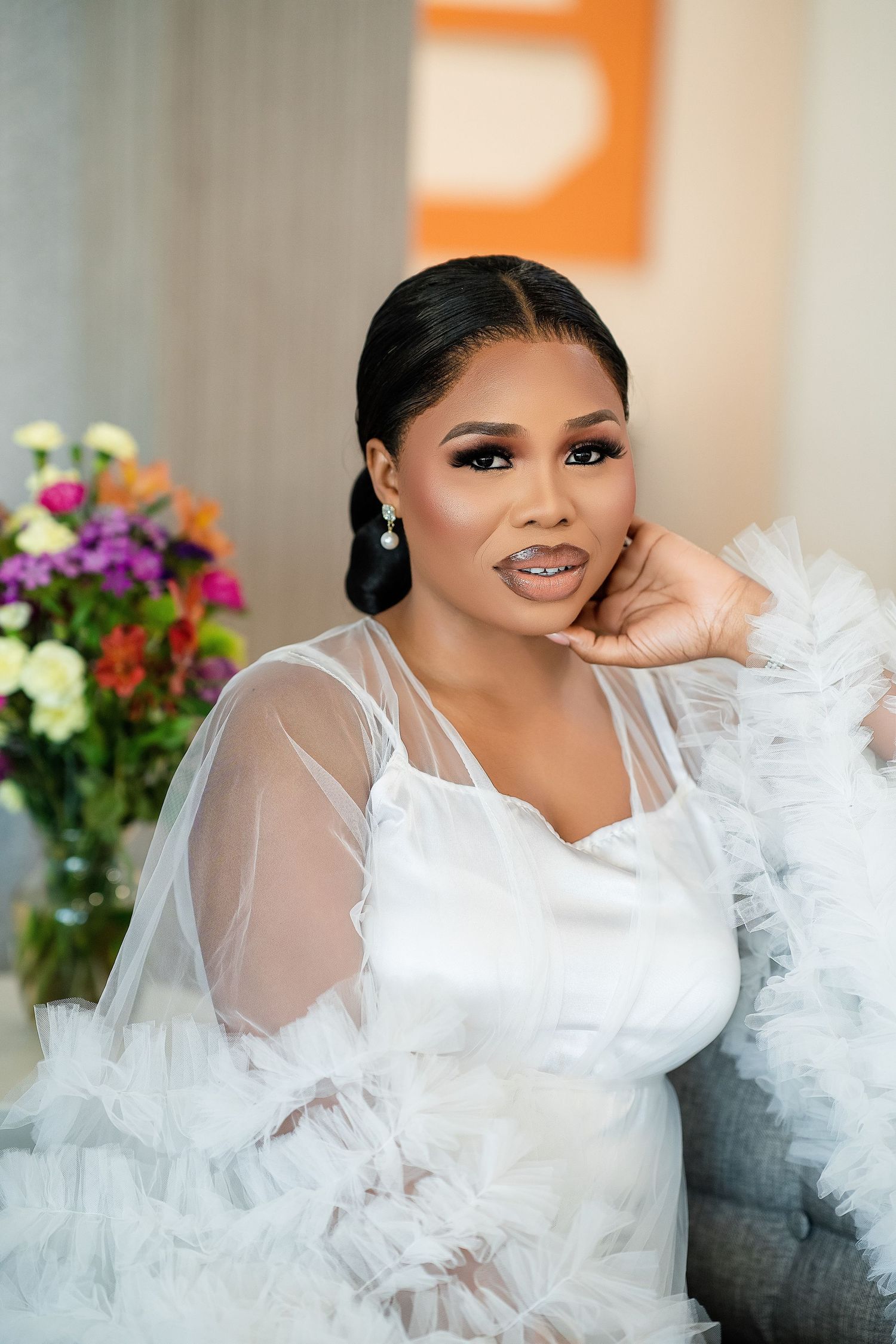 Glamorous bridal photoshoot with white tulle gown and colorful floral arrangements in the background.