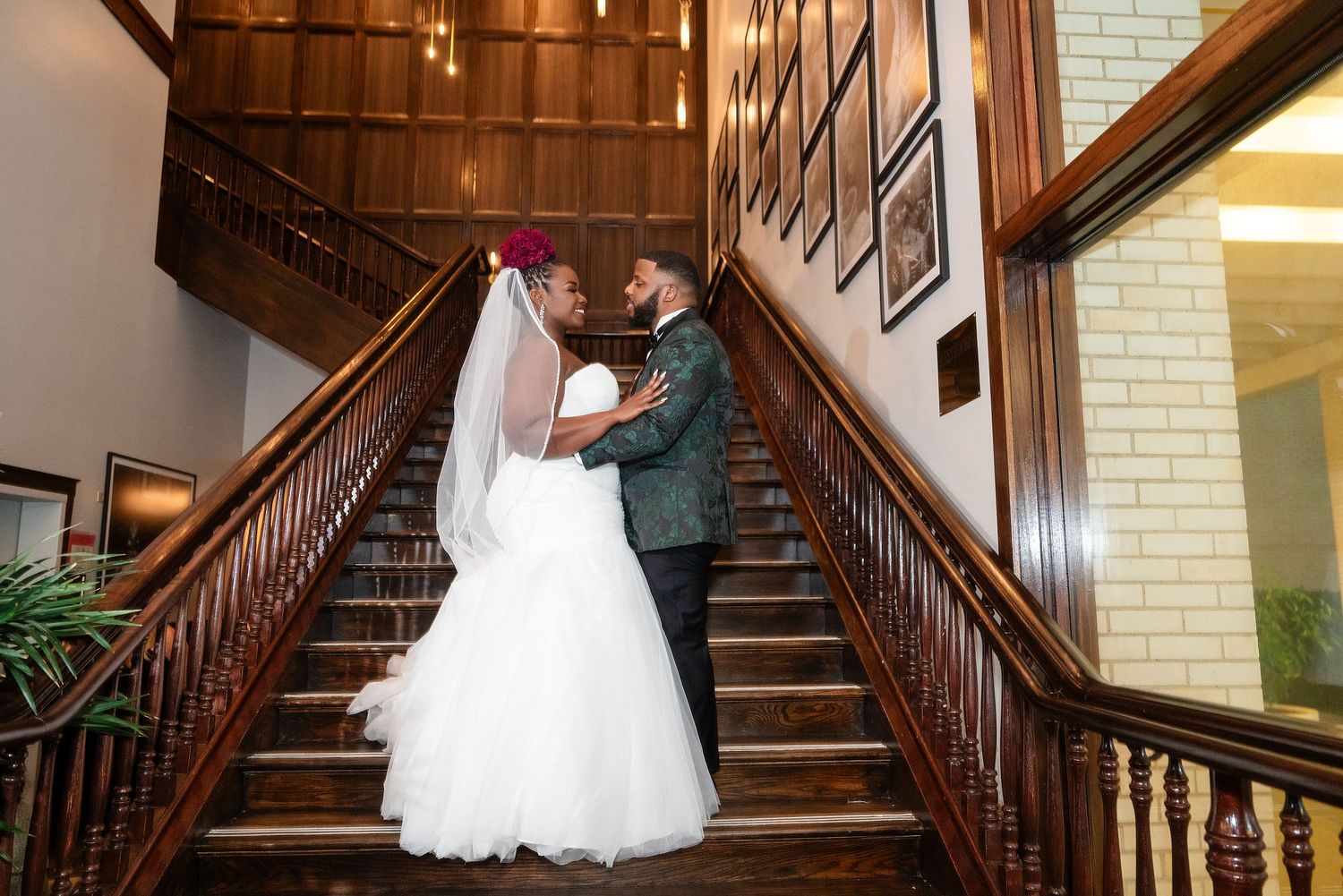 White wedding dress displayed on dark wooden staircase with warm lighting.