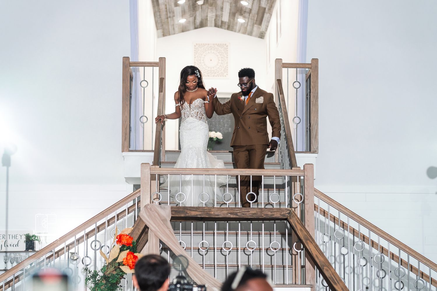 Wedding couple poses on white balcony stairs with elegant architectural details.