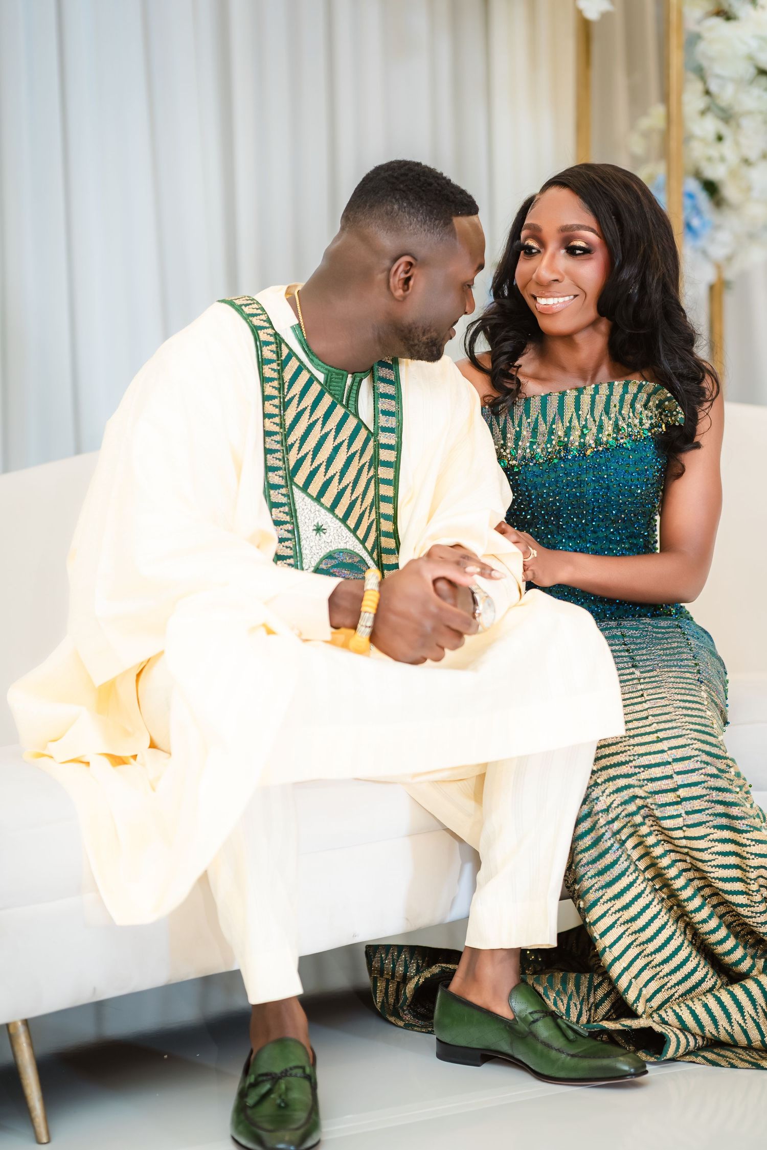A couple in coordinating green and white traditional Nigerian attire share an intimate moment during their wedding celebration.