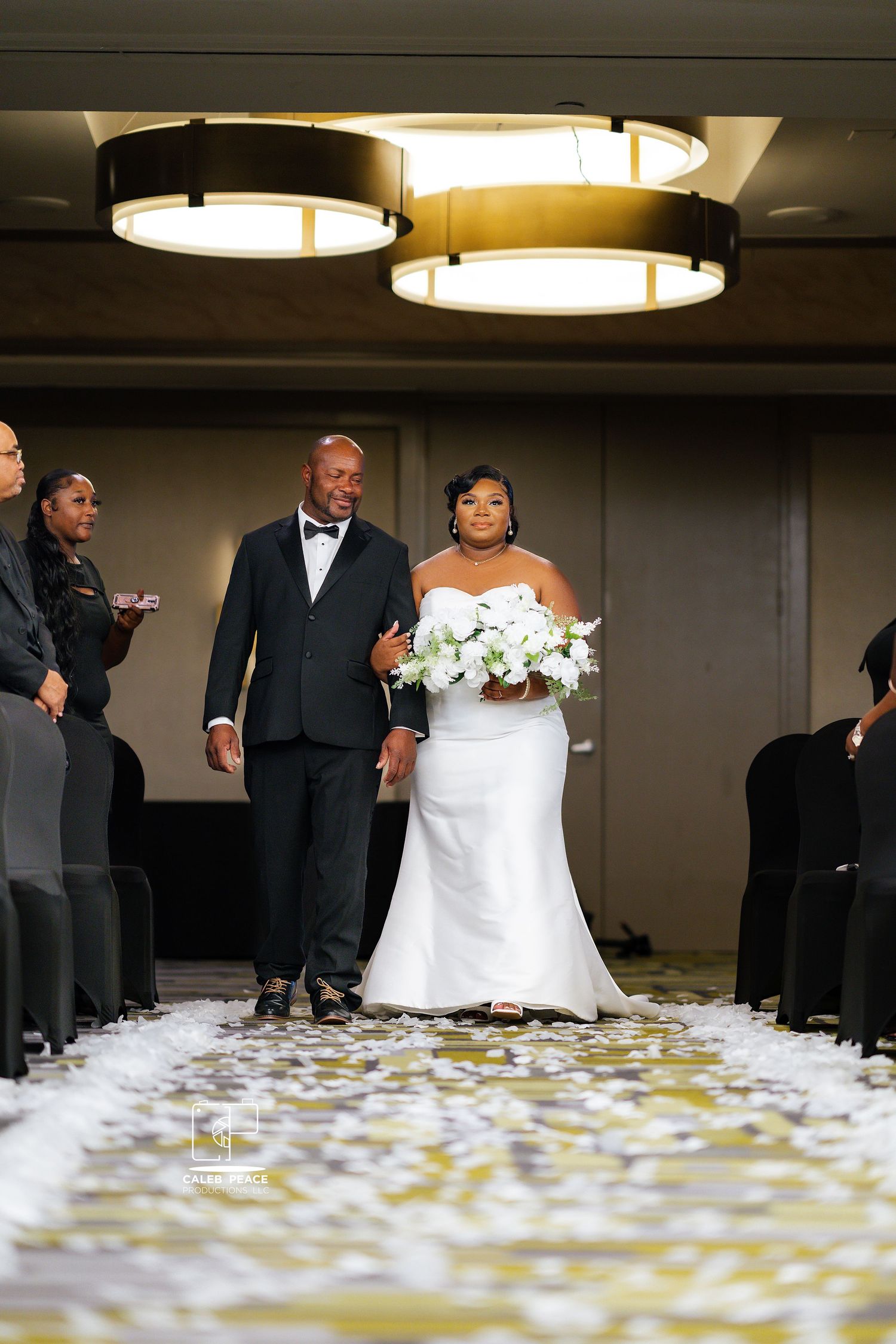 Wedding ceremony setup in an elegant ballroom with scattered petals along the aisle.