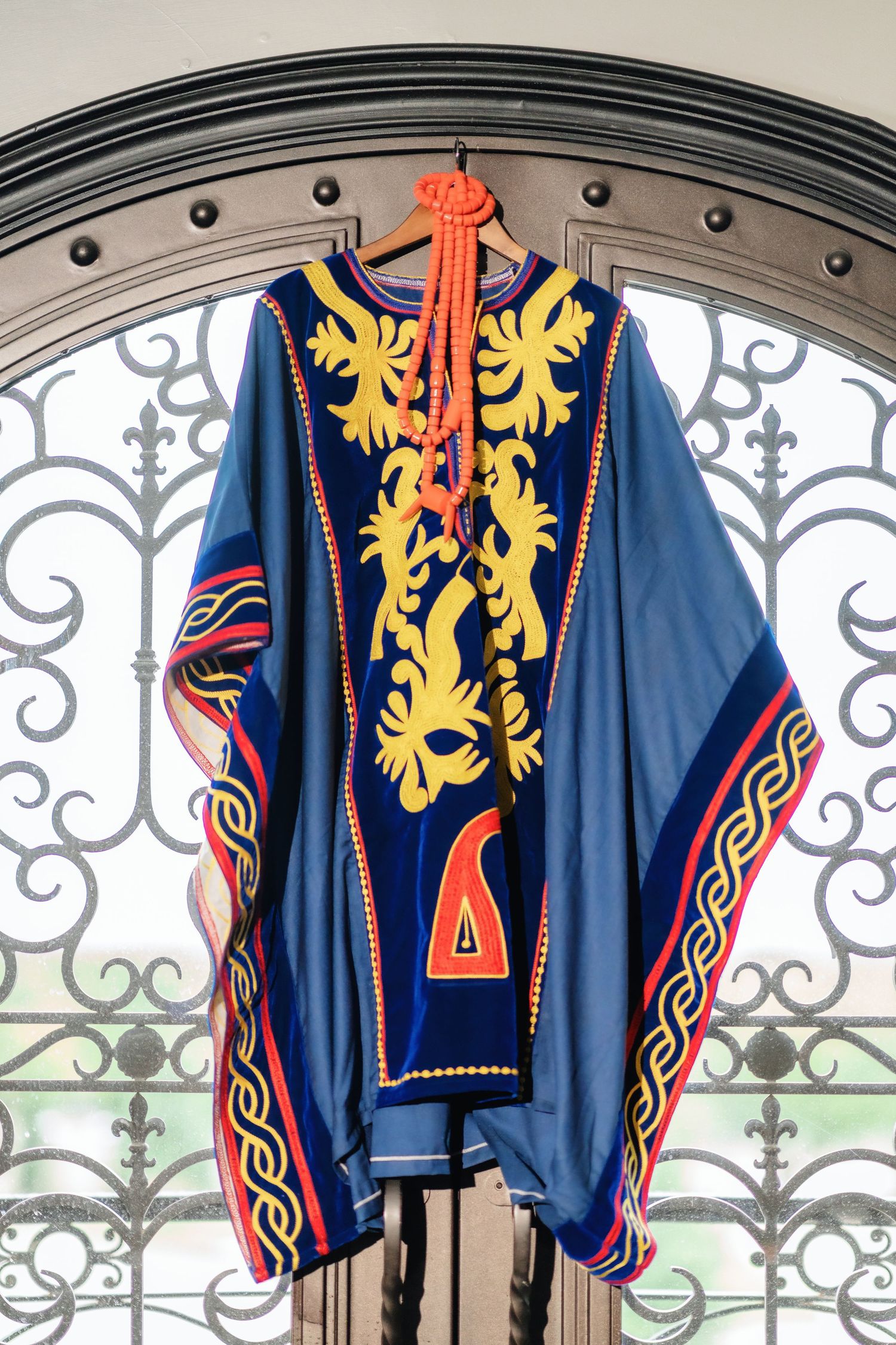 Traditional blue and gold ceremonial military uniform with ornate embroidered lions displayed against iron gates.