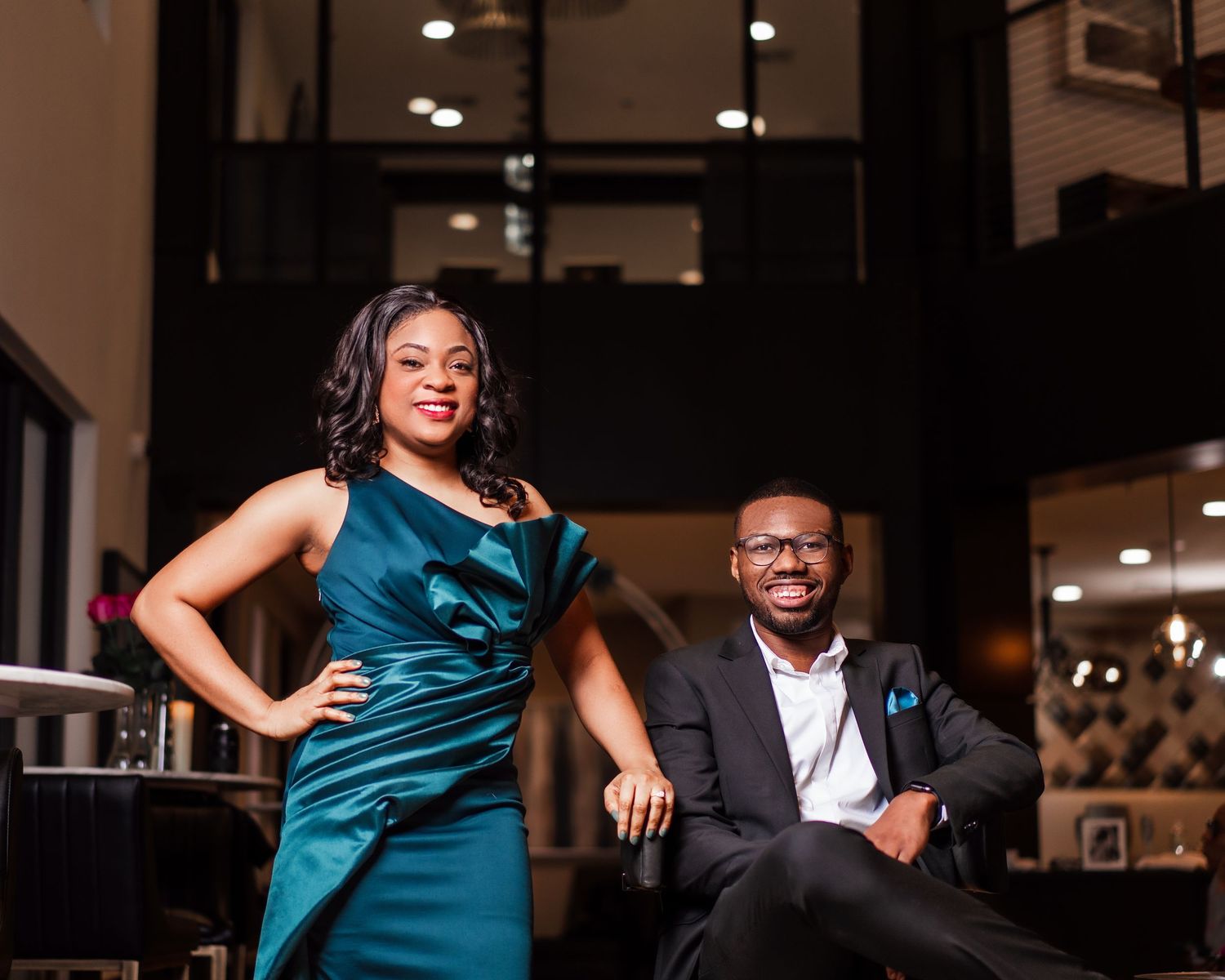 A couple poses together at an elegant event, with the woman wearing a teal evening gown and the man in a black suit.