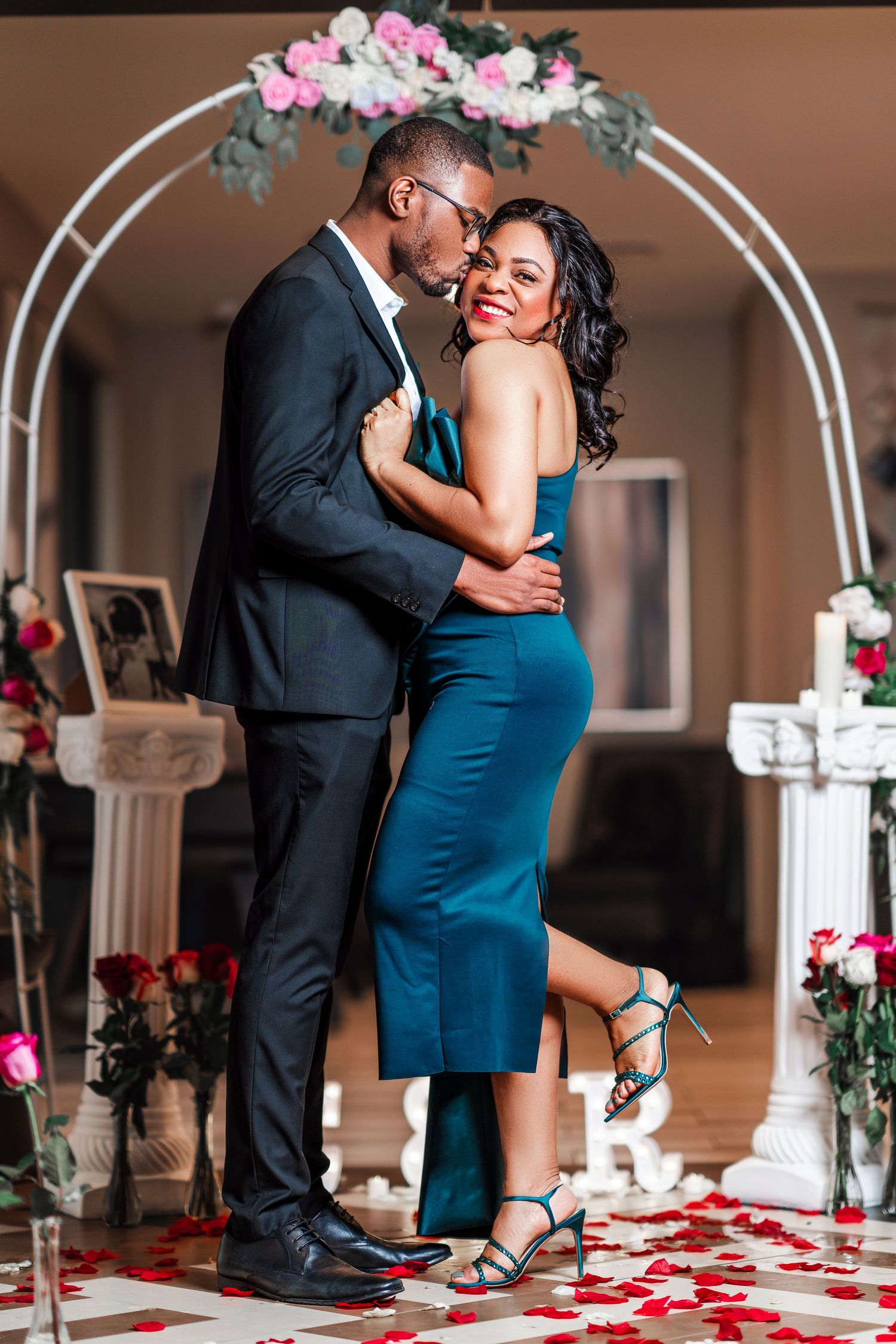 Romantic couple sharing intimate dance moments in an elegant venue decorated with floral arches and rose petals.