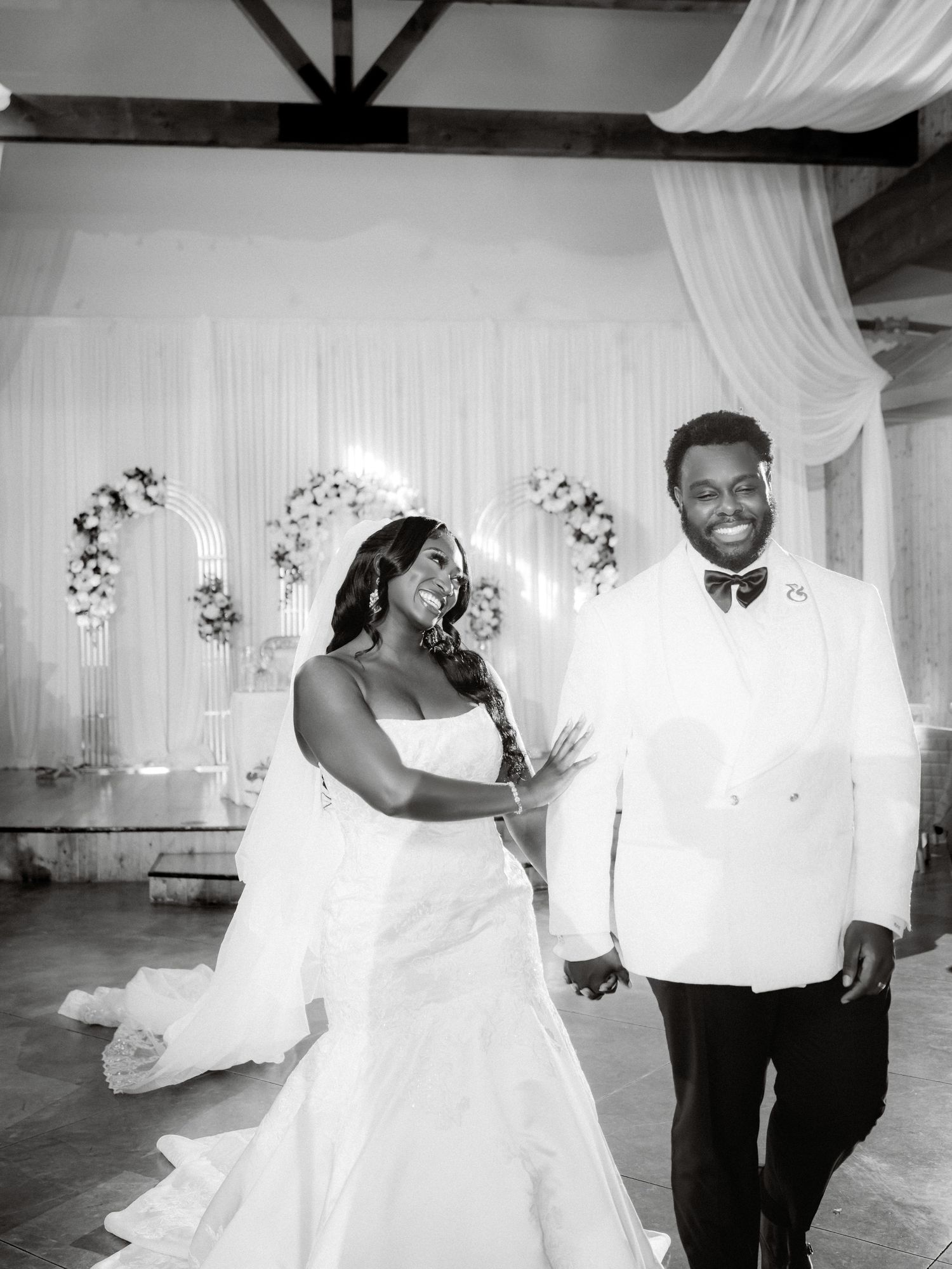 Black and white wedding photos capturing candid moments between newlyweds in an indoor venue.