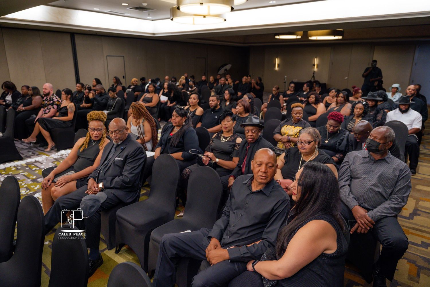Large wedding reception audience seated in formal attire in hotel conference room.