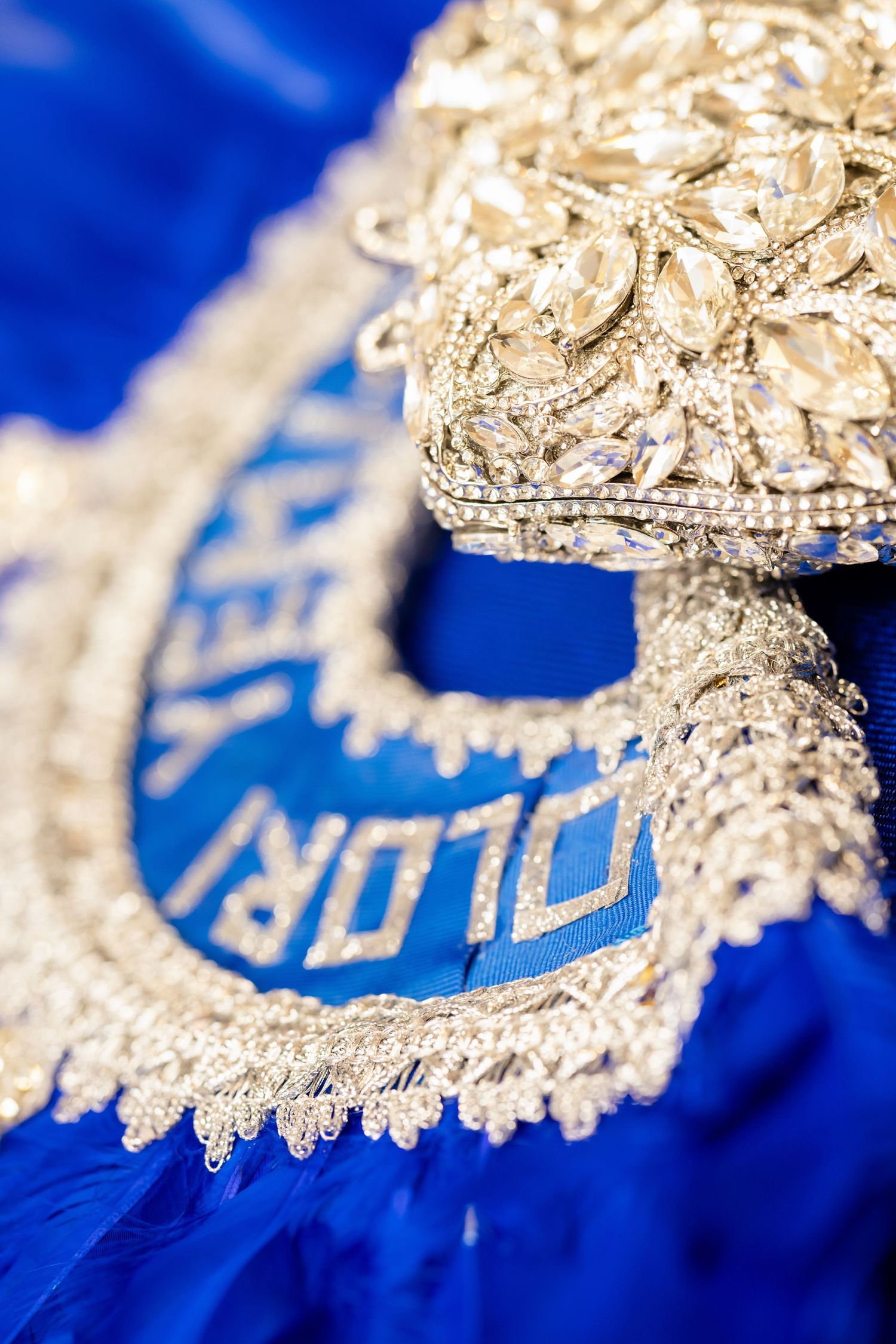 Close-up detail of gold embroidery on royal blue fabric with intricate patterns.