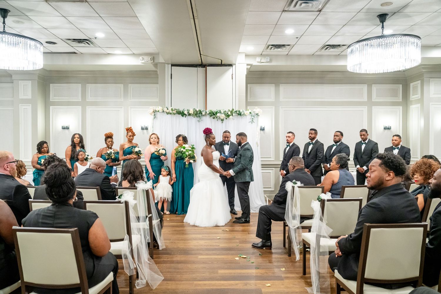 Wedding ceremony setup in a modern indoor venue with rows of white chairs.