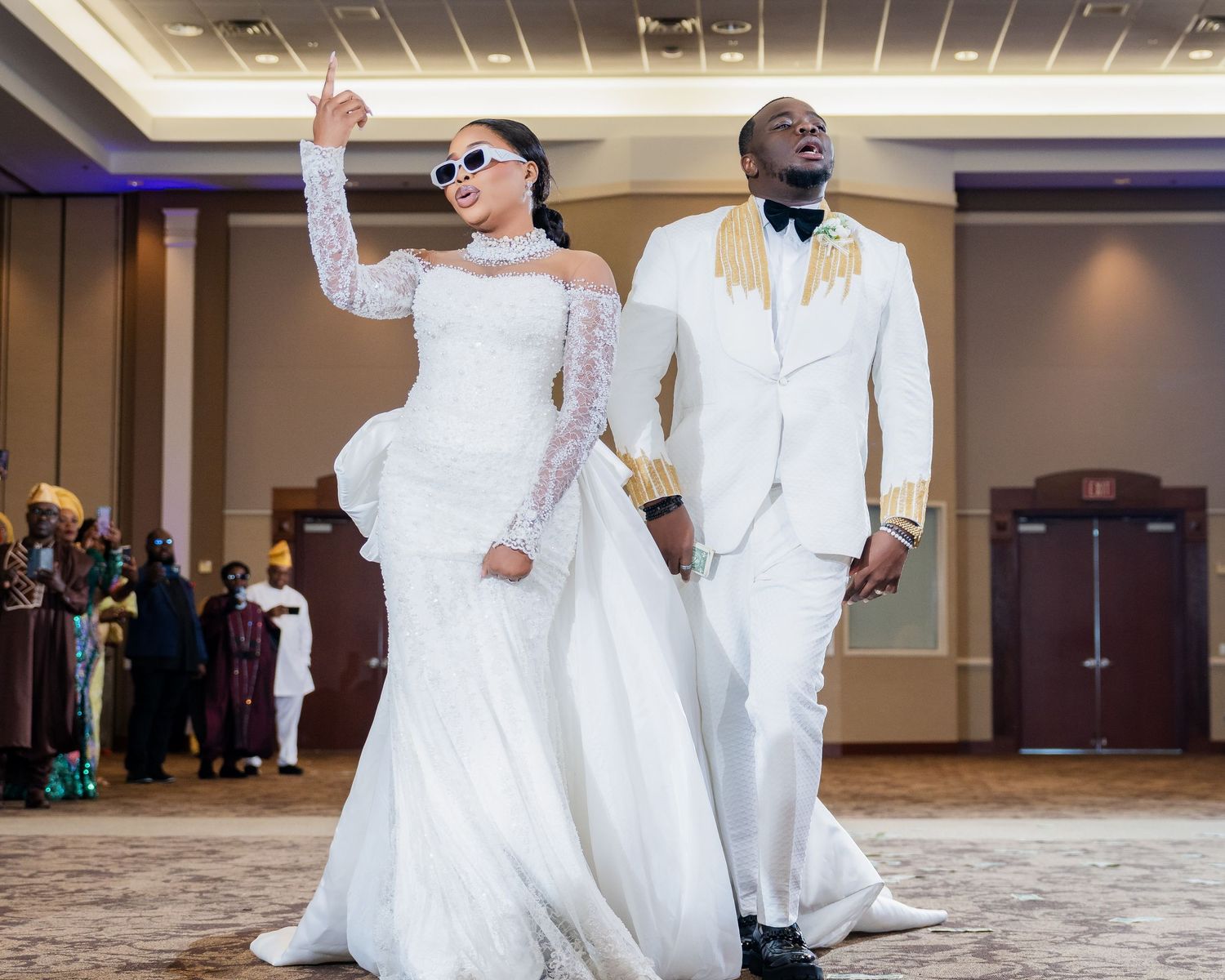 Wedding party members in white attire dance and celebrate together during a joyous reception celebration.