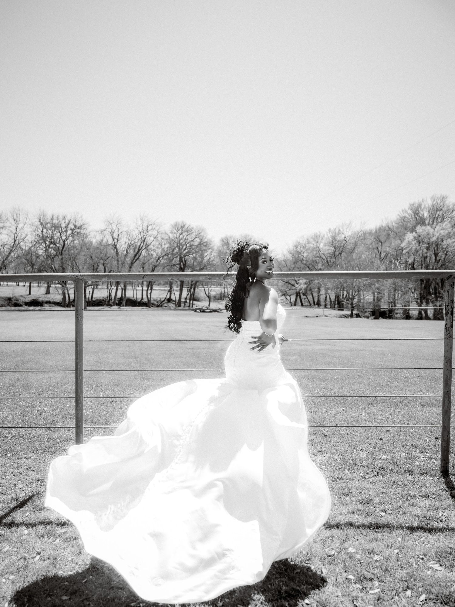 A flowing white dress billows dramatically across an open field with bare winter trees in the background.