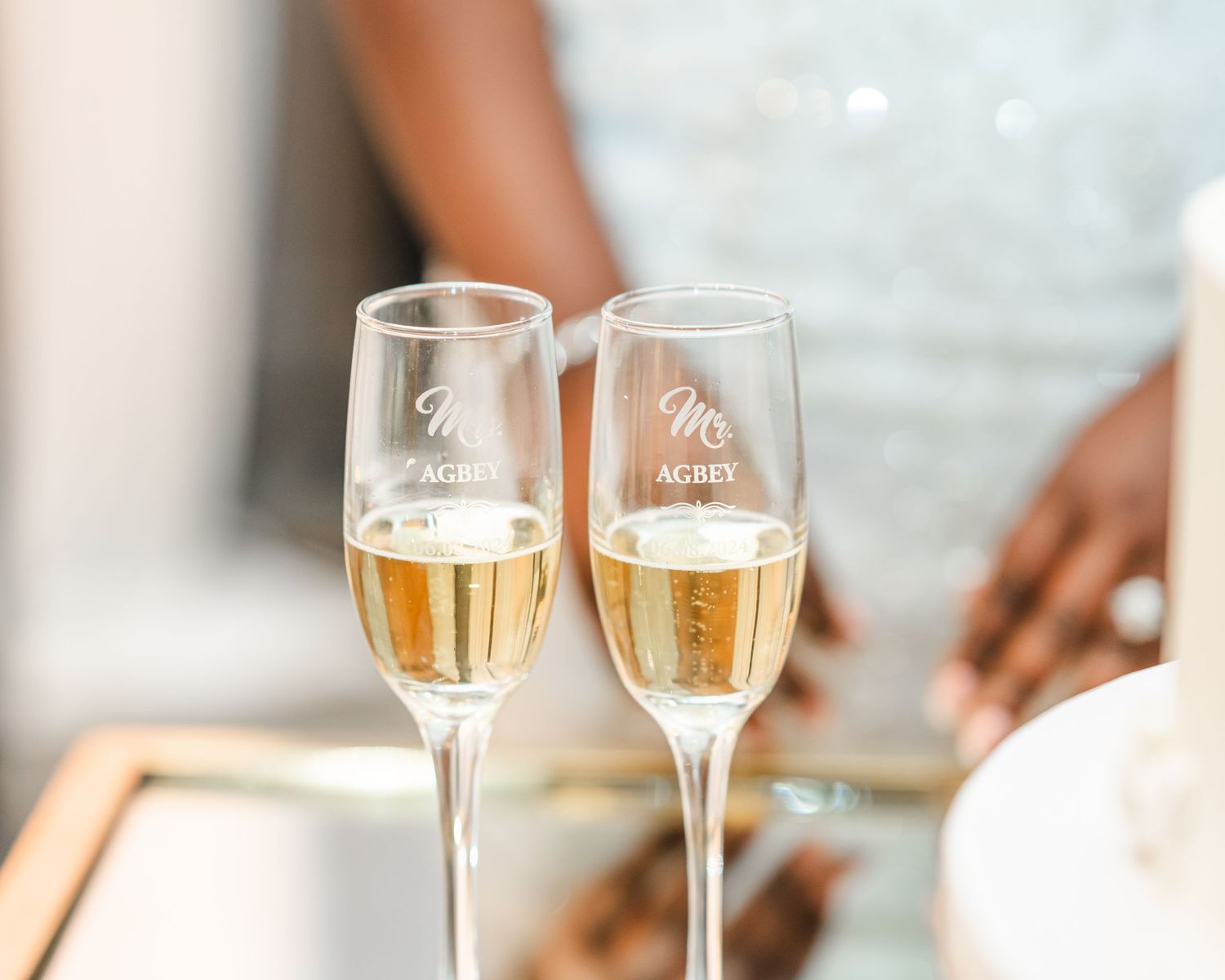Two champagne flutes filled with sparkling wine sit on an elegant table setting.