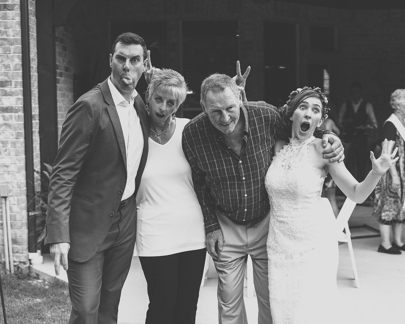 A black and white photo capturing wedding guests in a candid celebratory moment.