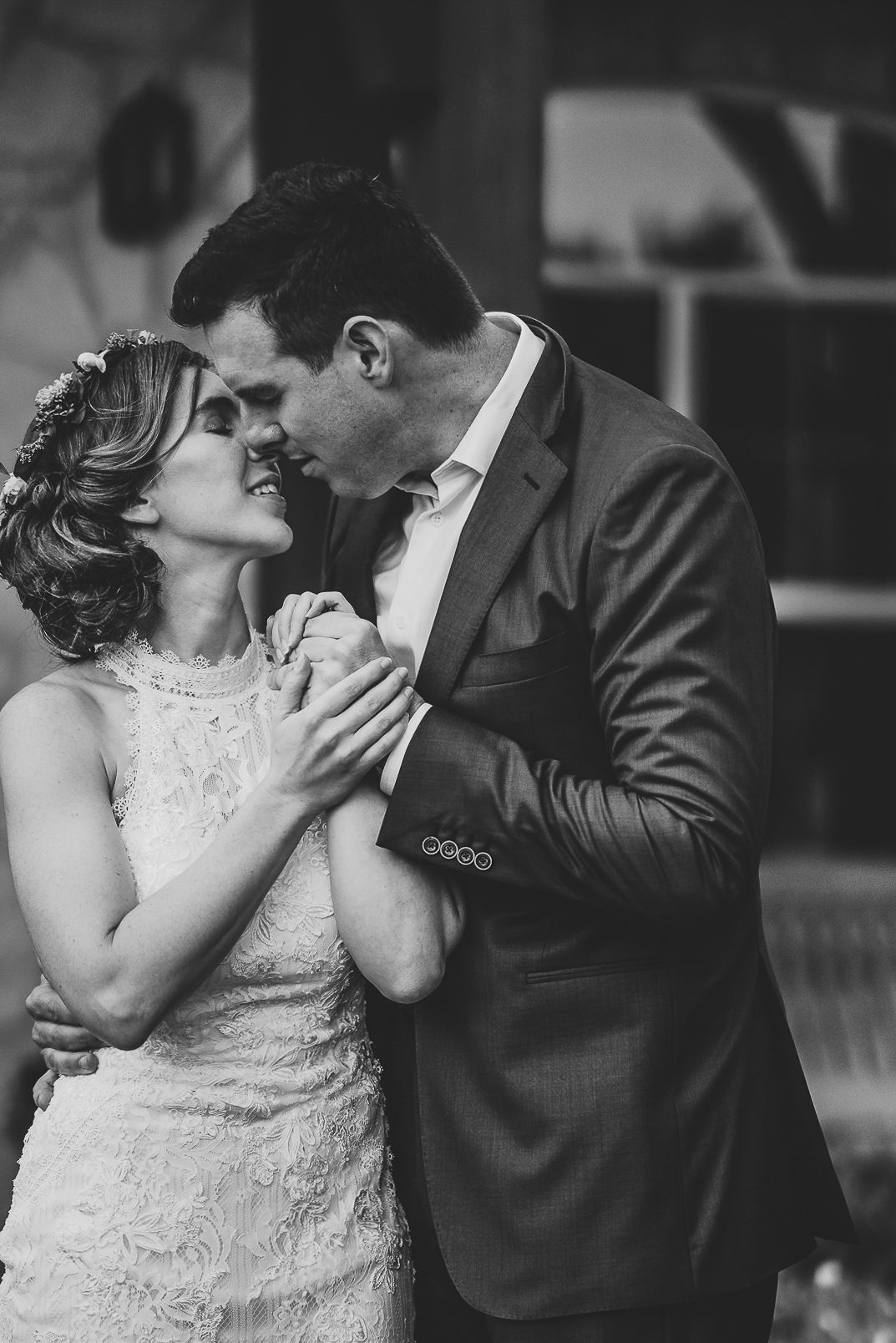 A romantic black and white wedding photo showing a tender moment between newlyweds in formal attire.