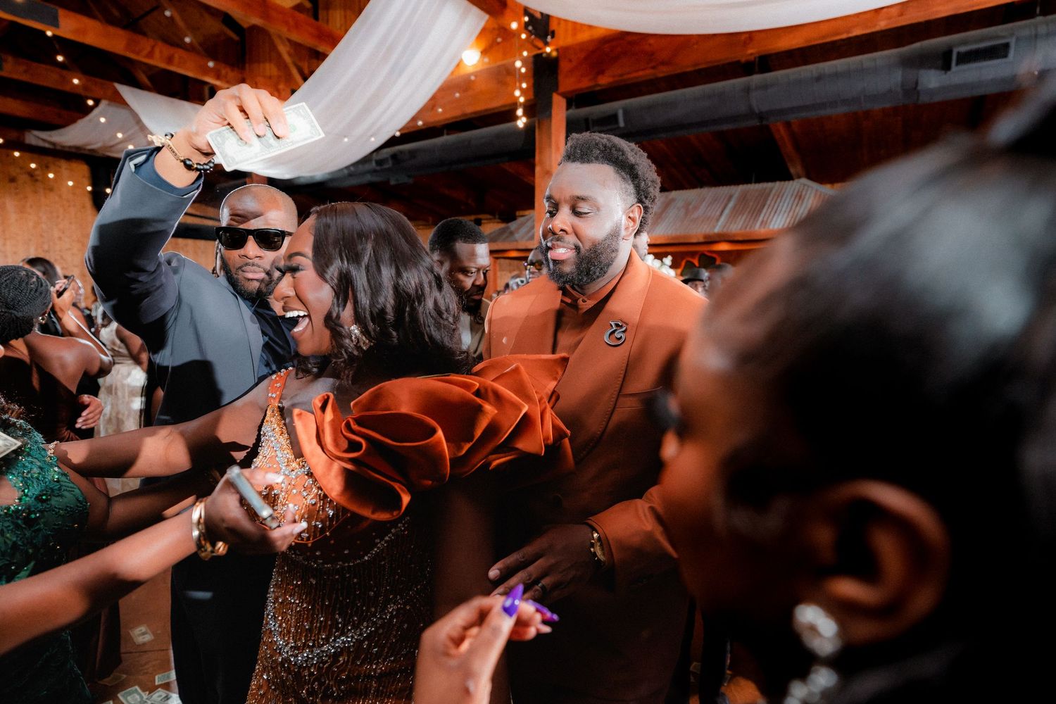 Wedding guests enjoying a lively dance party under warm lighting at an indoor reception.