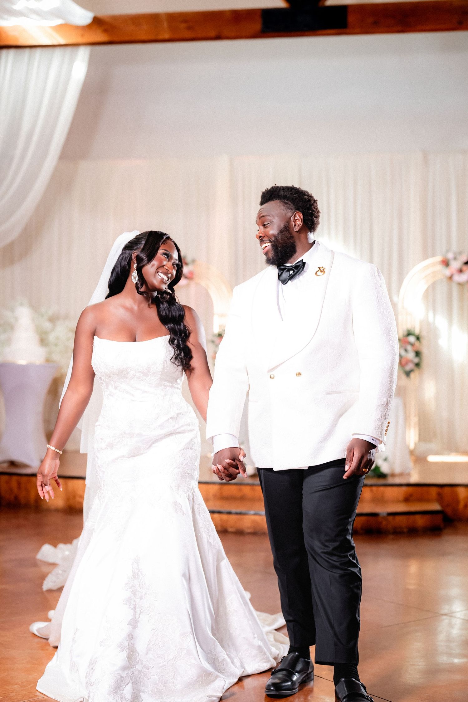 Newlyweds share their first dance in an elegant white-draped reception venue.